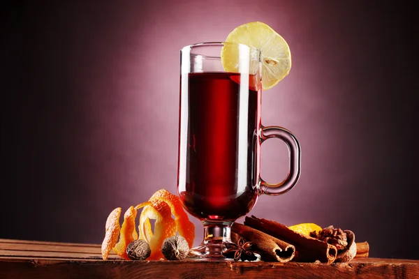 Grzane wino w szkło, przyprawy i cytryny na fioletowym tle — Zdjęcie stockowe