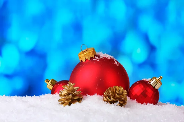 Beautiful blue Christmas balls and cones in snow on blue background — Stock Photo, Image
