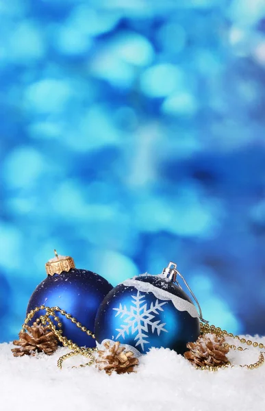 Krásný modrý vánoční koule a šišky ve sněhu na modrém pozadí — Stock fotografie