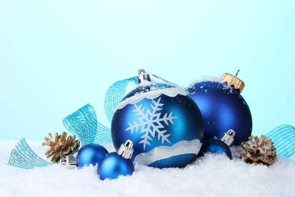 Güzel mavi Noel topları ve koni içinde kar üzerinde mavi arka plan — Stok fotoğraf