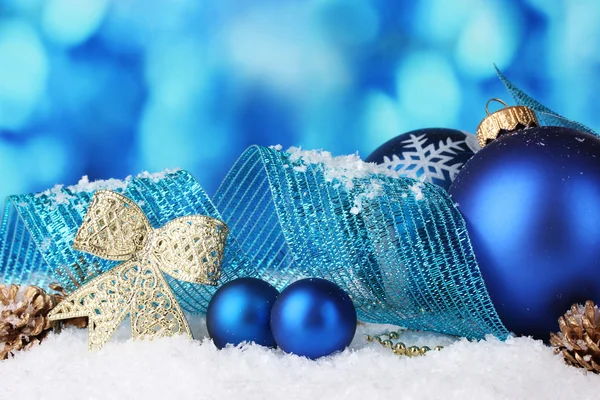 Vackra blå julgranskulor och kottar i snö på blå bakgrund — Stockfoto