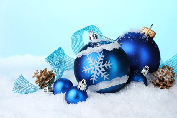 Красивые голубые рождественские шары и конусы в снегу на голубом фоне — стоковое фото