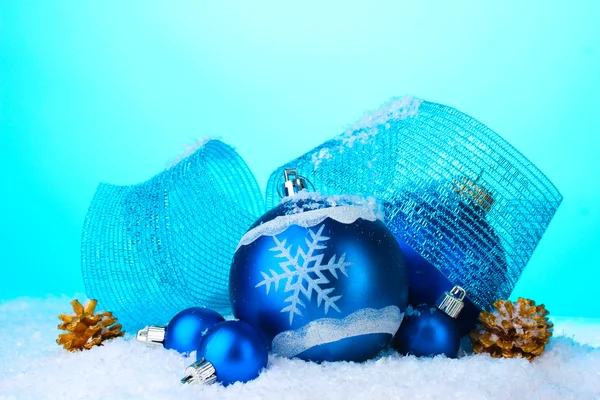 Vackra blå julgranskulor och kottar i snö på blå bakgrund — ストック写真