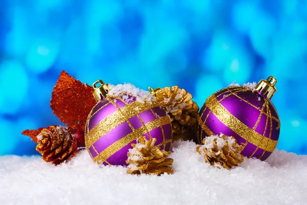 Belas bolas de Natal roxo e ramo na neve no fundo azul — Fotografia de Stock