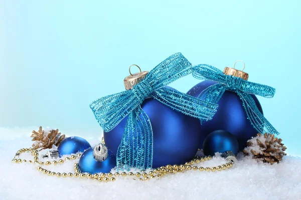 Krásný modrý vánoční koule a šišky na sněhu na modrém pozadí — Stock fotografie