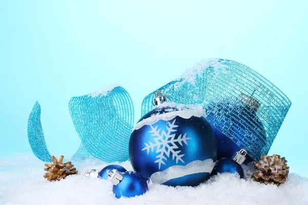 ลูกบอลคริสต์มาสสีฟ้าที่สวยงามและกรวยในหิมะบนพื้นหลังสีฟ้า — ภาพถ่ายสต็อก