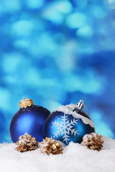 Belas bolas de Natal azuis e cones na neve no fundo azul — Fotografia de Stock