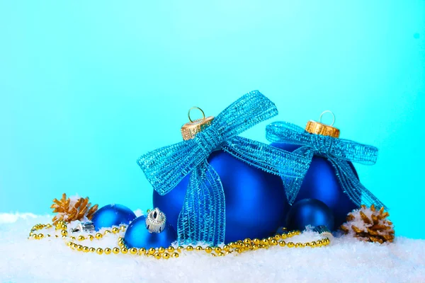 Belas bolas de Natal azuis e cones na neve no fundo azul — Fotografia de Stock