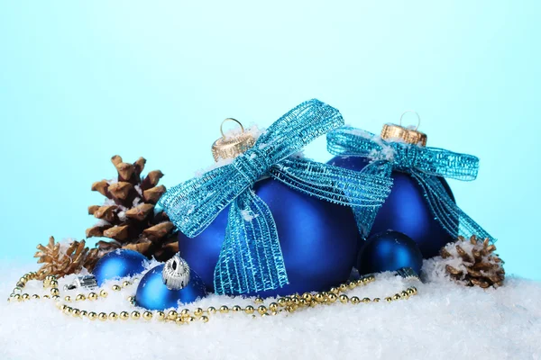 Güzel mavi Noel topları ve konileri üzerinde kar mavi zemin üzerine — Stok fotoğraf