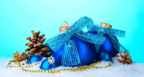Belles boules de Noël bleues et cônes sur neige sur fond bleu — Photo