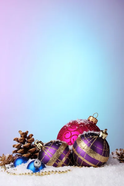 Hermosas bolas de Navidad y conos en la nieve sobre fondo brillante — Foto de Stock