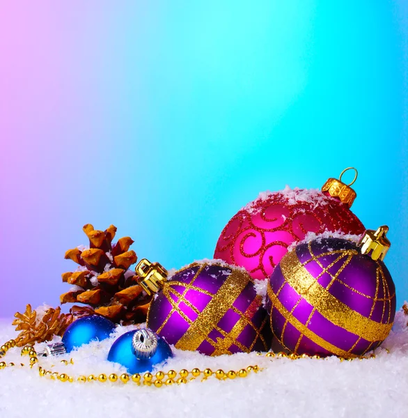 Schöne Weihnachtskugeln und -kegel auf Schnee auf hellem Hintergrund — Stockfoto