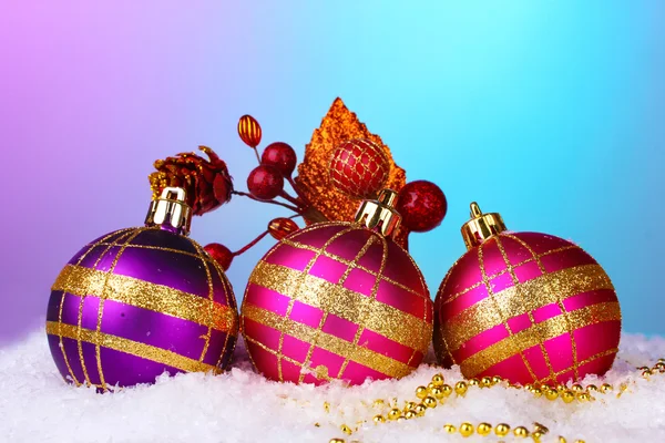 Beautiful Christmas balls and cone on snow on bright background — Stok fotoğraf