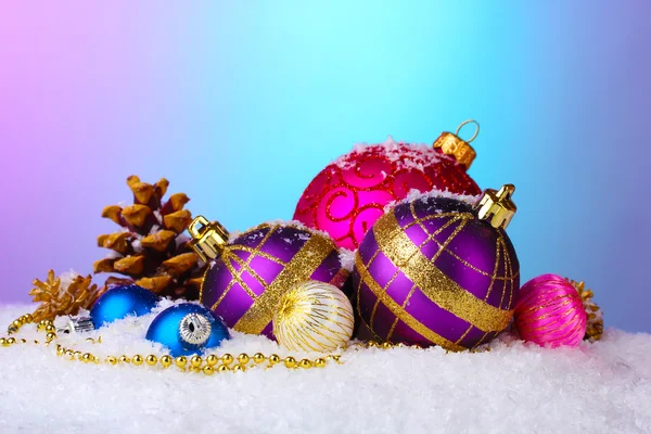 Vackra julgranskulor och kottar på snö på ljus bakgrund — Stockfoto