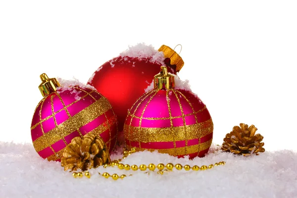 Beautiful pink and red Christmas balls and cones on snow isolated on white — Stock Photo, Image