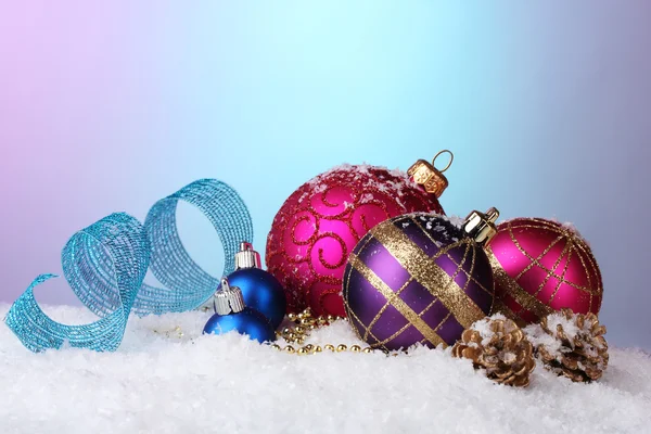 Vackra julgranskulor och kottar på snö på ljus bakgrund — Stockfoto