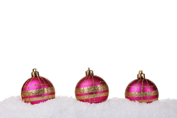 Hermosas bolas de Navidad de color rosa en la nieve aislada en blanco — Foto de Stock