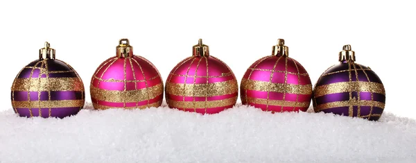 Hermosas bolas de Navidad rosa y púrpura en la nieve aislada en blanco —  Fotos de Stock