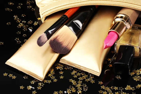 Hermosa bolsa de maquillaje dorado y cosméticos aislados en negro —  Fotos de Stock