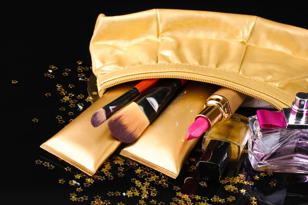 Hermosa bolsa de maquillaje dorado y cosméticos aislados en negro —  Fotos de Stock