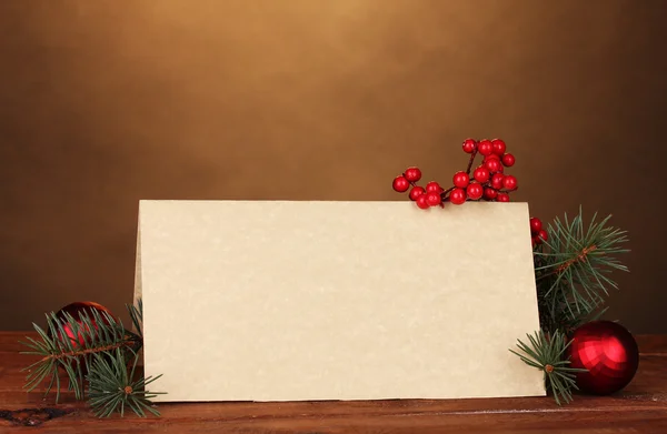 Postal en blanco, bolas de Navidad y abeto sobre mesa de madera sobre respaldo marrón —  Fotos de Stock