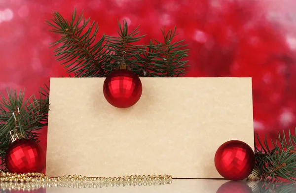 Lege briefkaart, kerstballen en Spar-boom op rode achtergrond — Stockfoto