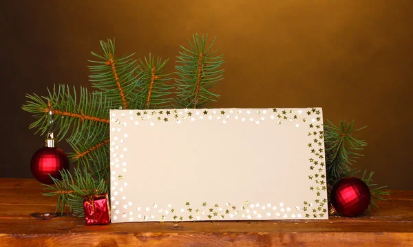 Blank postcard, Christmas balls and fir-tree on wooden table on brown backg — Stock Photo, Image