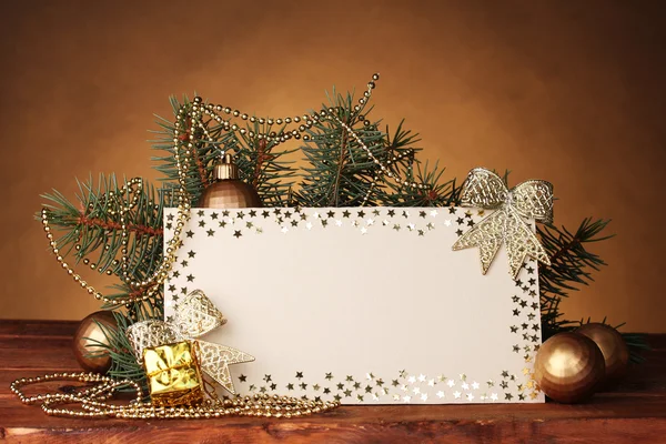 Cartolina bianca, palline di Natale e abete su tavolo di legno su dorso marrone — Foto Stock