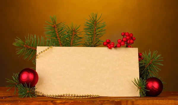 Postal en blanco, bolas de Navidad y abeto sobre mesa de madera sobre respaldo marrón —  Fotos de Stock
