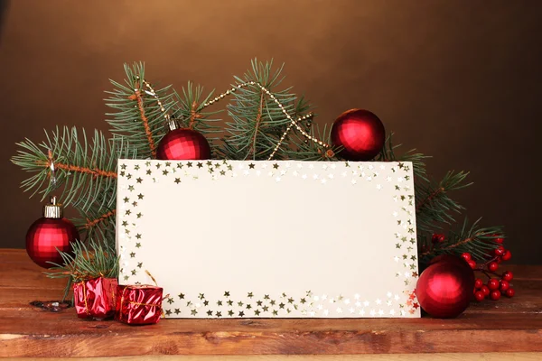 Cartão postal em branco, bolas de Natal e abeto na mesa de madeira no backg marrom — Fotografia de Stock
