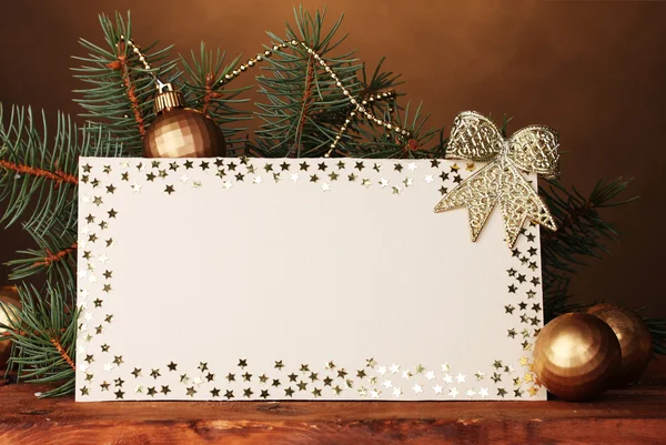 Cartão postal em branco, bolas de Natal e abeto na mesa de madeira no backg marrom — Fotografia de Stock