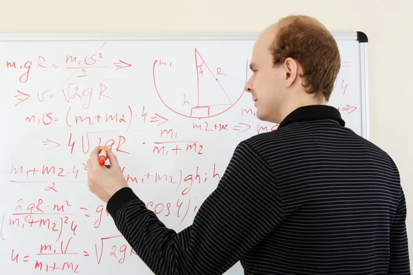 Muž píše matematické vzorce na bílou tabuli — Stock fotografie