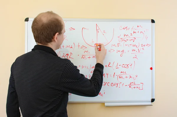 Man writing math formulas on a white-board — Stock Photo, Image