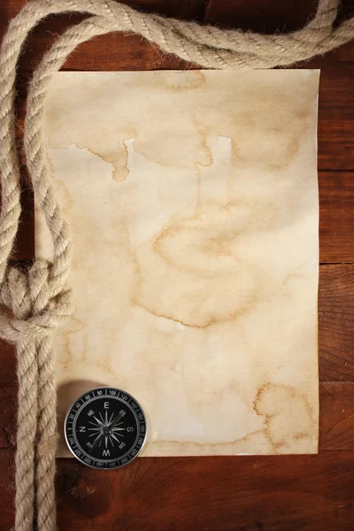 Papel velho, bússola e corda em uma mesa de madeira — Fotografia de Stock