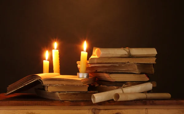 Pilha de livros antigos com vela e pergaminho no escuro — Fotografia de Stock