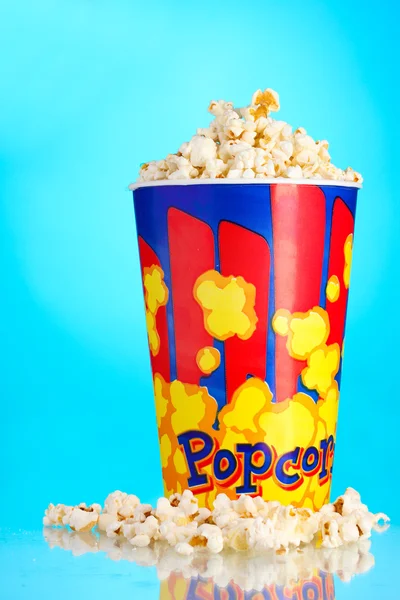 Full bucket of popcorn on blue — Stock Photo, Image