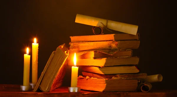 Mucchio di vecchi libri con candela e scorrimento al buio — Foto Stock