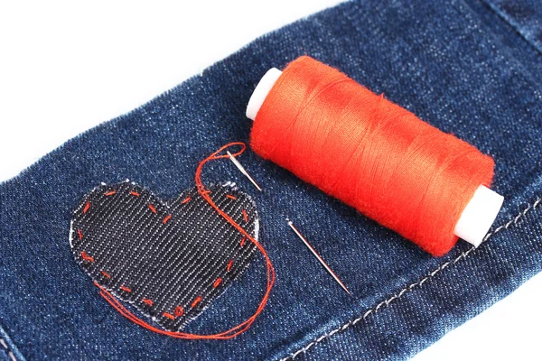 Herzförmiger Patch auf Jeans mit Nadel und Faden in Nahaufnahme — Stockfoto