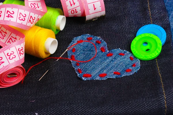 Hjärtformade lapp på jeans med trådar och knappar närbild — Stockfoto