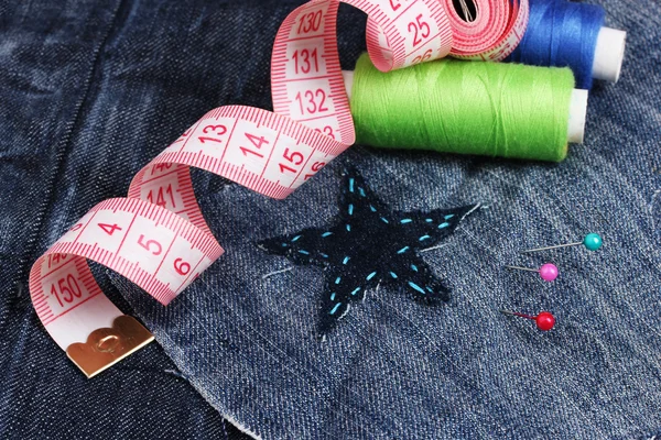 Star-shaped patch on jeans with threads and buttons closeup — Stock Photo, Image