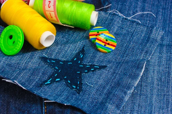 Star-shaped patch on jeans with threads and buttons closeup — Stock Photo, Image