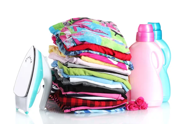 Pilha de roupas coloridas e ferro elétrico com detergente isolado em branco — Fotografia de Stock