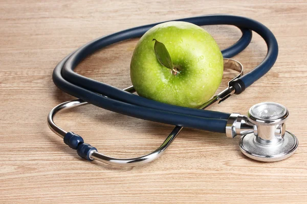 医学の聴診器と木製の背景に青リンゴ — ストック写真