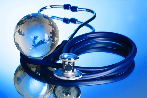 Globus und Stethoskop auf blauem Hintergrund — Stockfoto