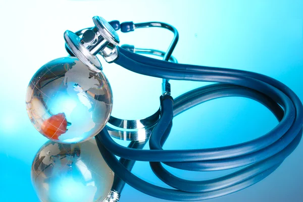 Globe en stethoscoop op blauw — Stockfoto