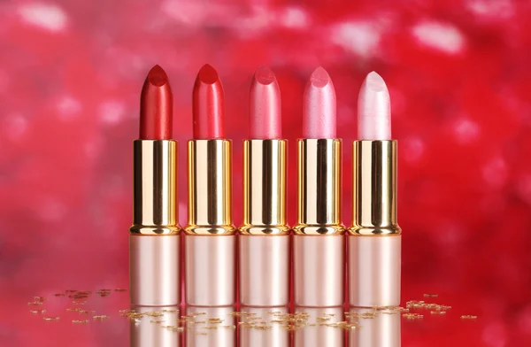 Mooie lippenstiften op rode achtergrond — Stockfoto