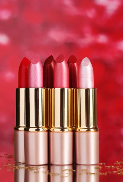 Hermosos lápices labiales sobre fondo rojo —  Fotos de Stock