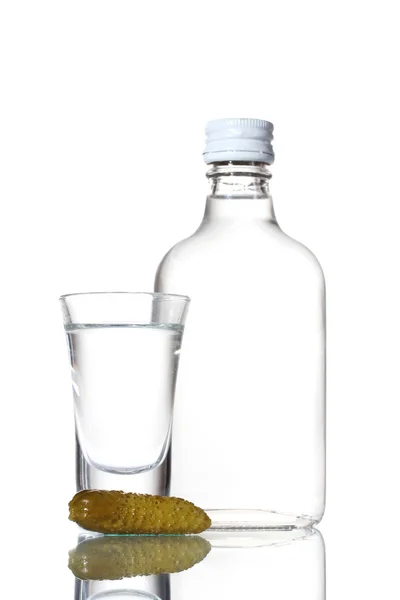 Butelka wódki i lampka z ogórka na białym tle — Zdjęcie stockowe