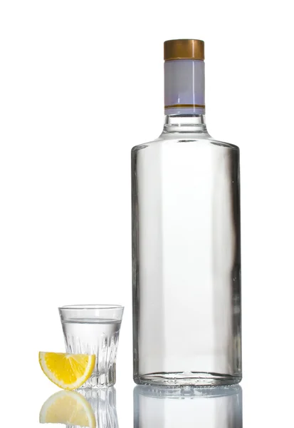 Butelka wódki i lampka z cytryny na białym tle — Zdjęcie stockowe