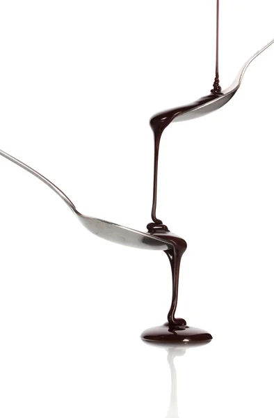 Chocolate poured into a spoon and from it to another spoon isolated on whit — Stock Photo, Image